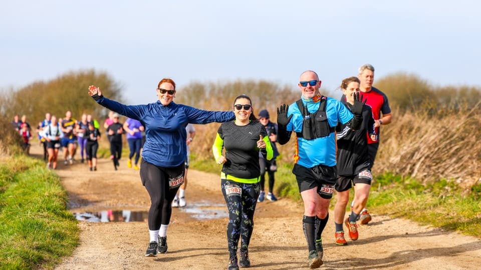 A group of runners smiling and waving during a race